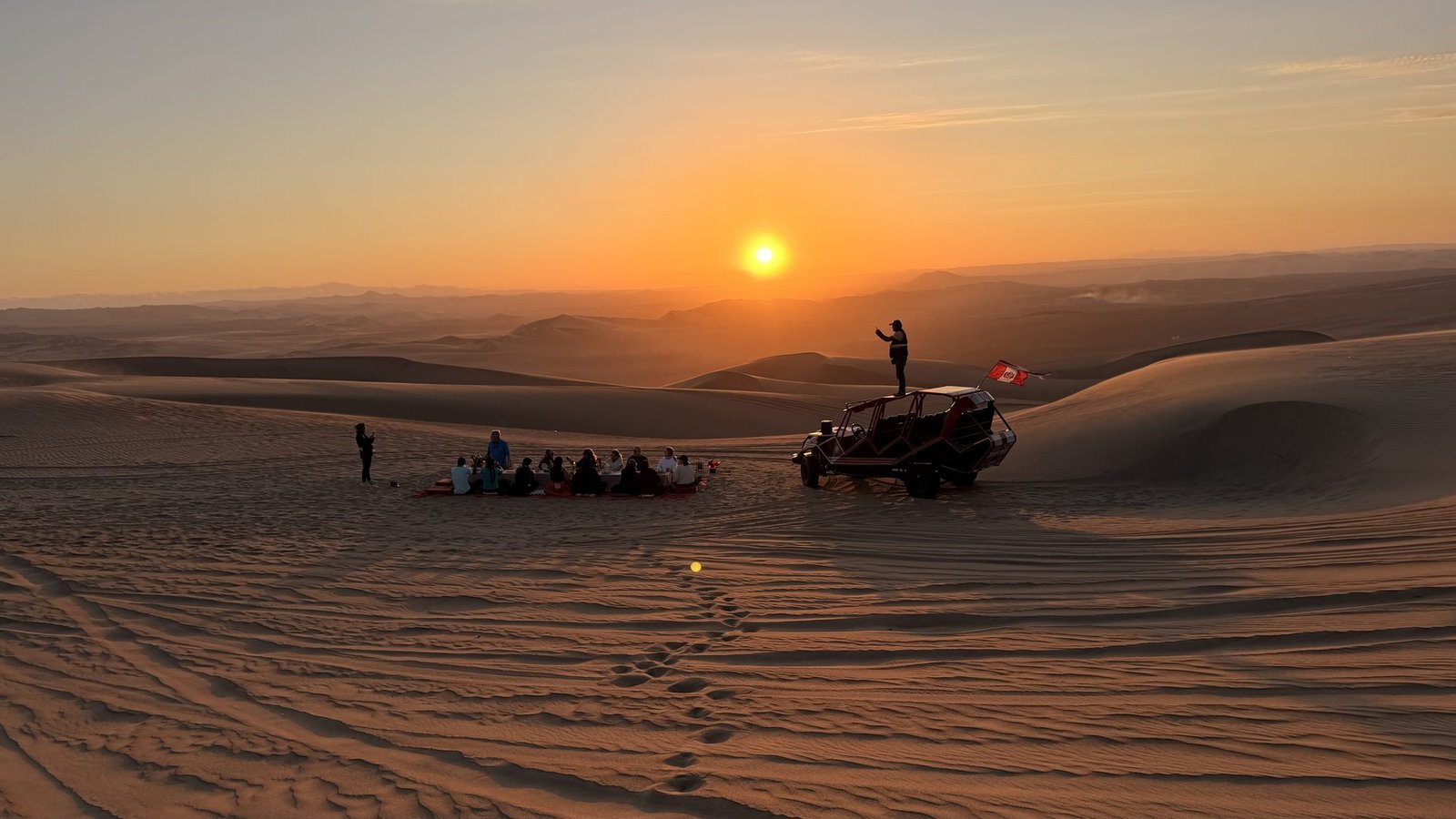 Sunset over the Huacachina dunes with a dune buggy